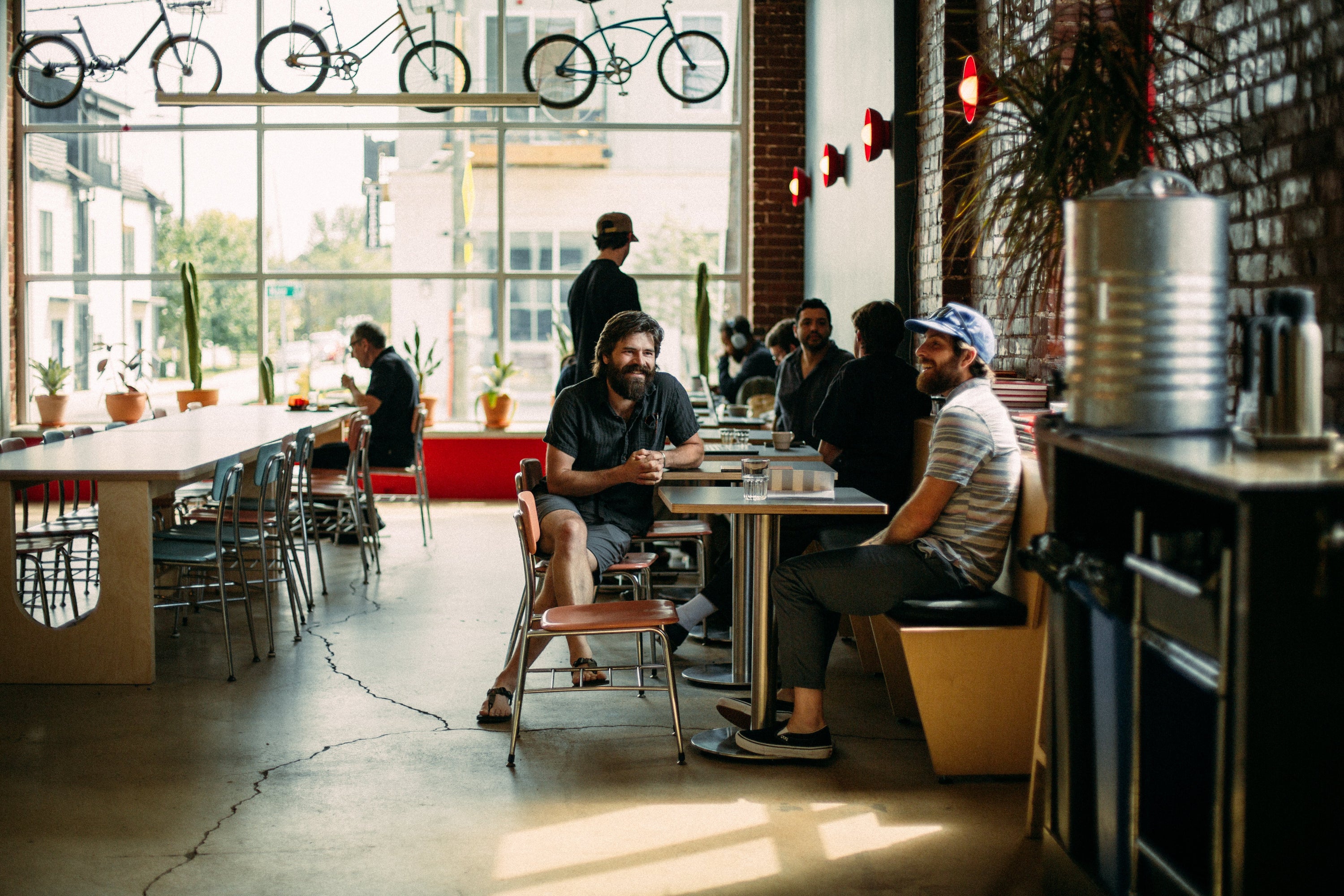 People sitting at tables in a modern cafe with bicycles on the wall.