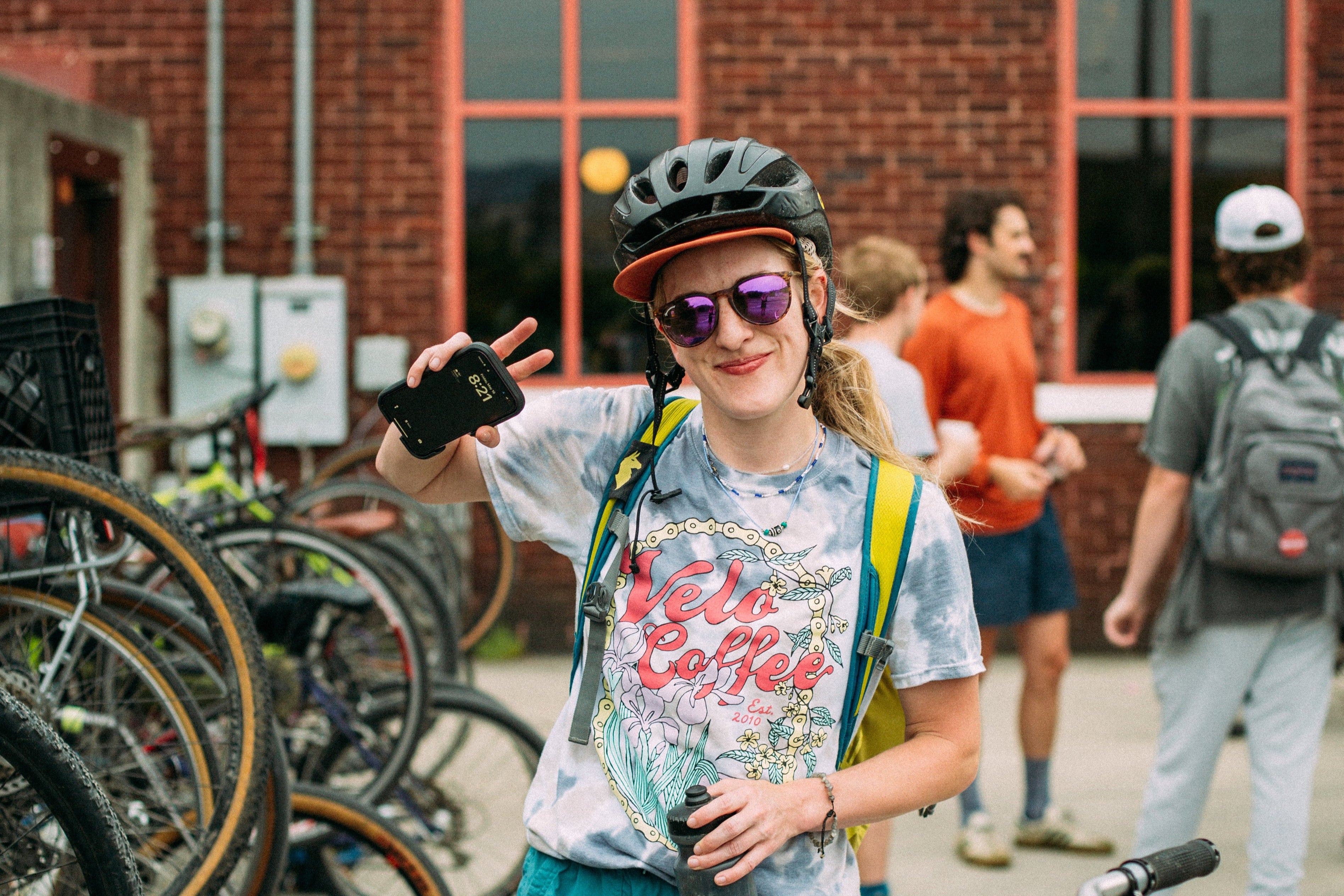 Person taking a selfie with bicycles and a brick building in the background