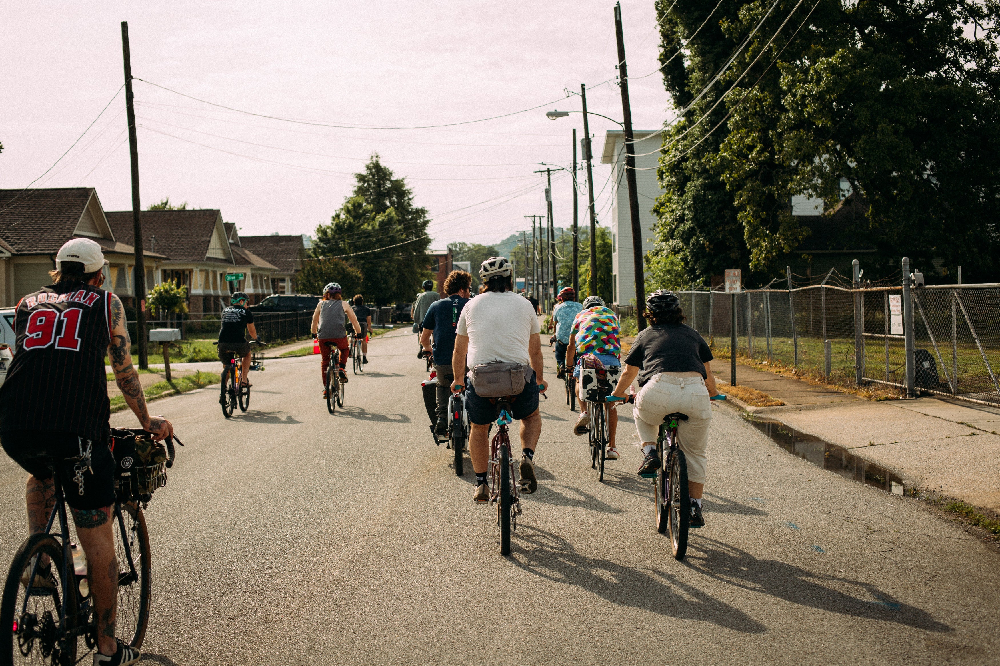 Group of cyclists riding down a residential street on a sunny day.